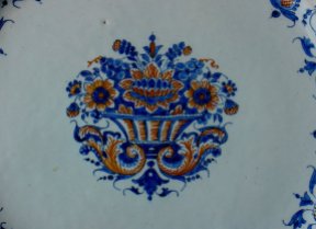 Detail of plate in Majolica (faience) a gran fuoco. Rouen, beginning of the 18th century Centre decoration detail—a basket of flowers in blue and ochre. Private Collection